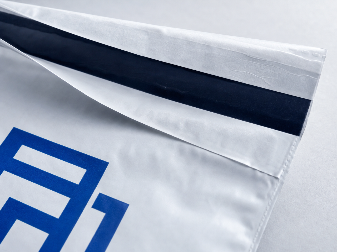 Macro view of the mailer flap, release liner, permanent self-seal strip, and textured film