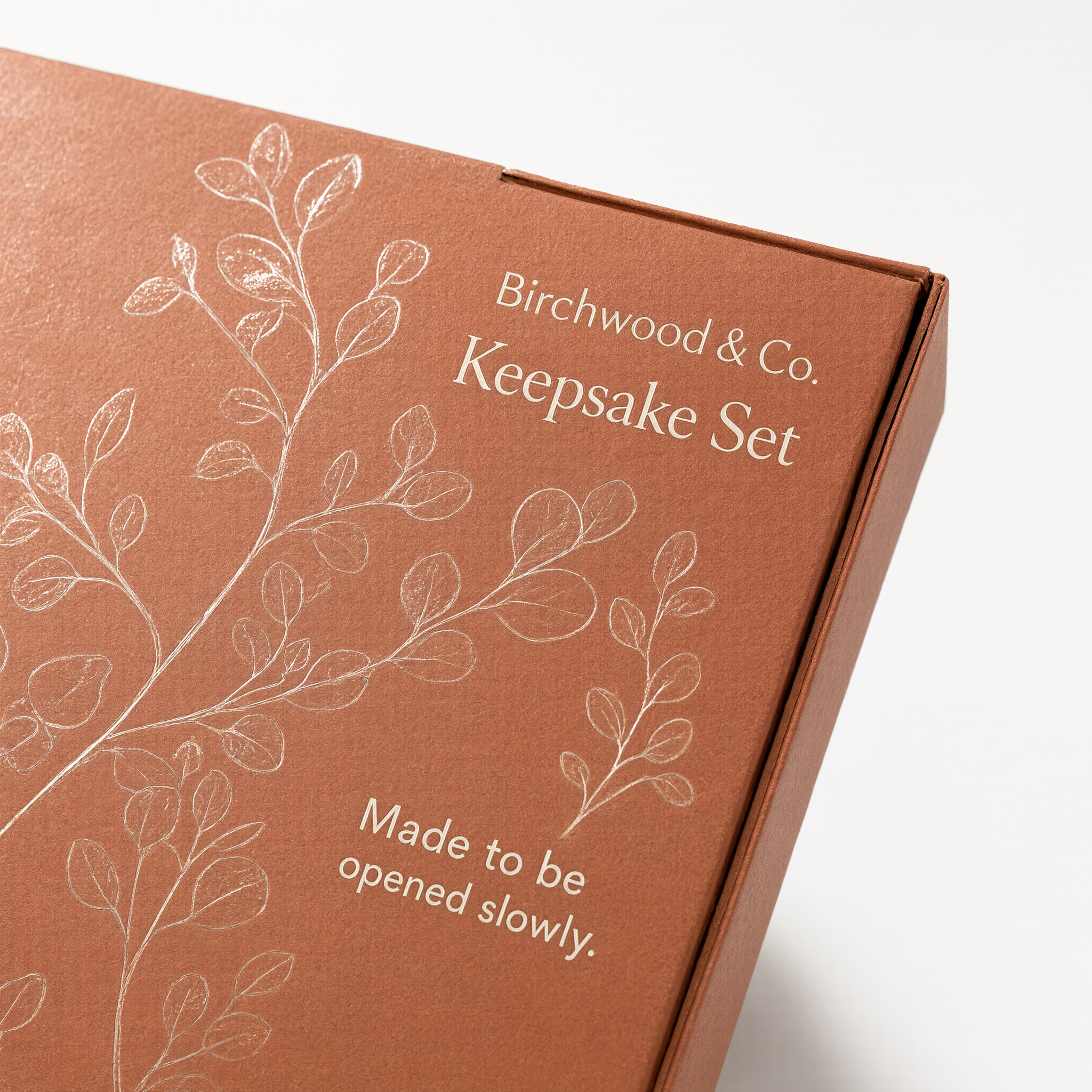 Close-up of spot UV gloss botanical linework against matte terracotta board texture